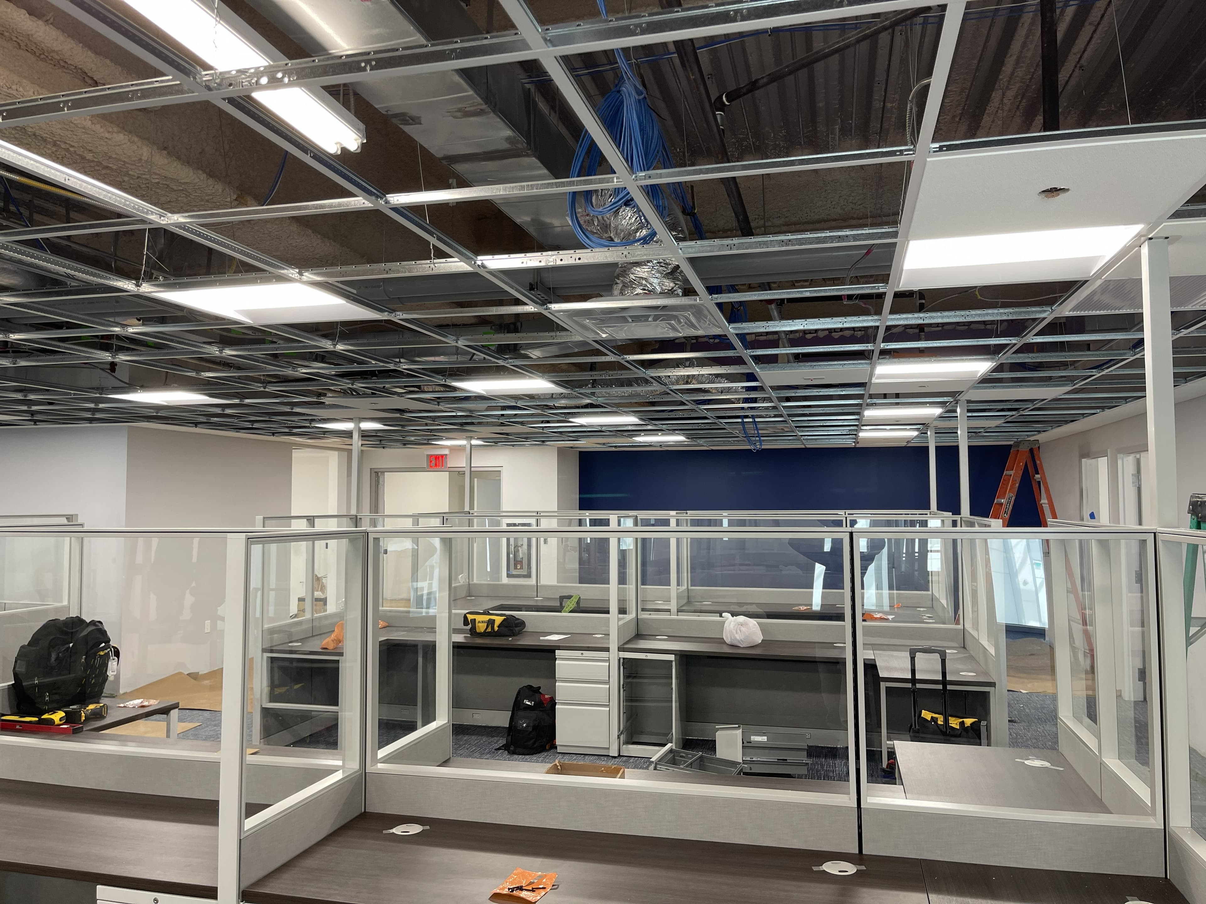 Modern office build-out with ceiling grid lighting and glass-panel workstations