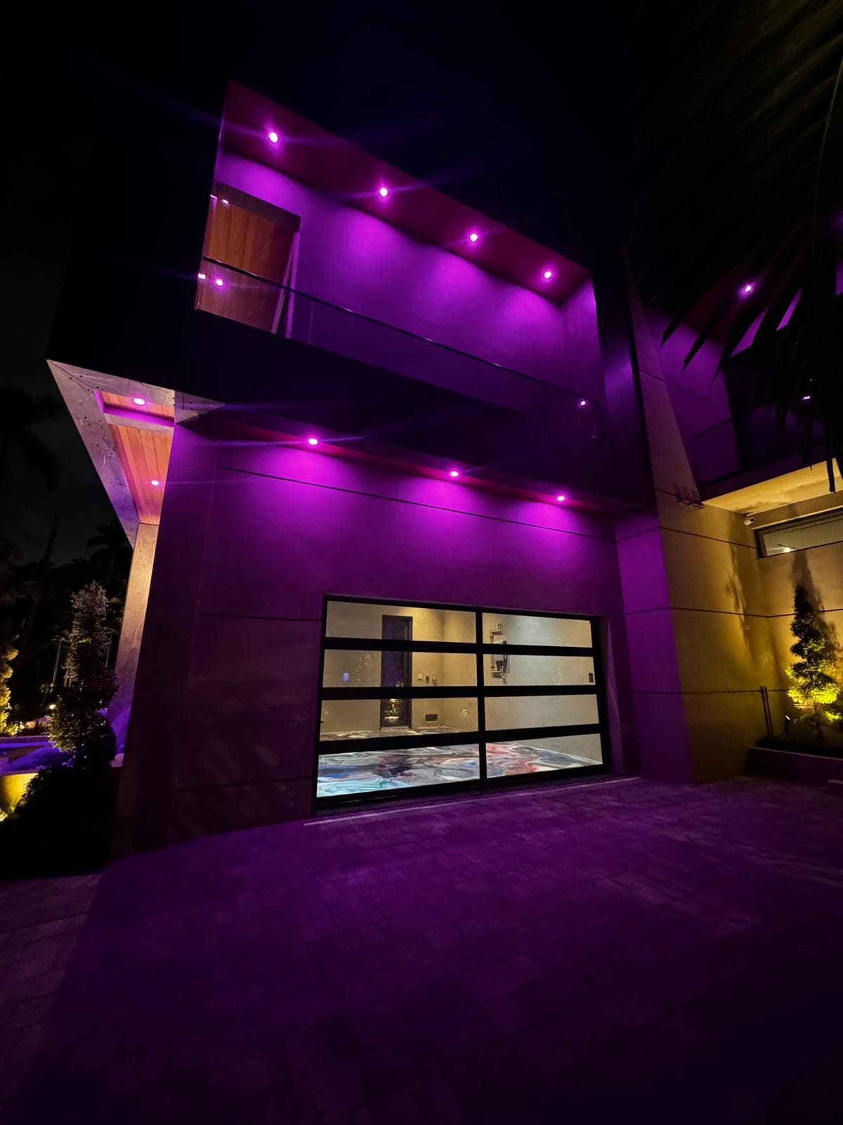 Residential exterior at night with color-changing architectural lighting