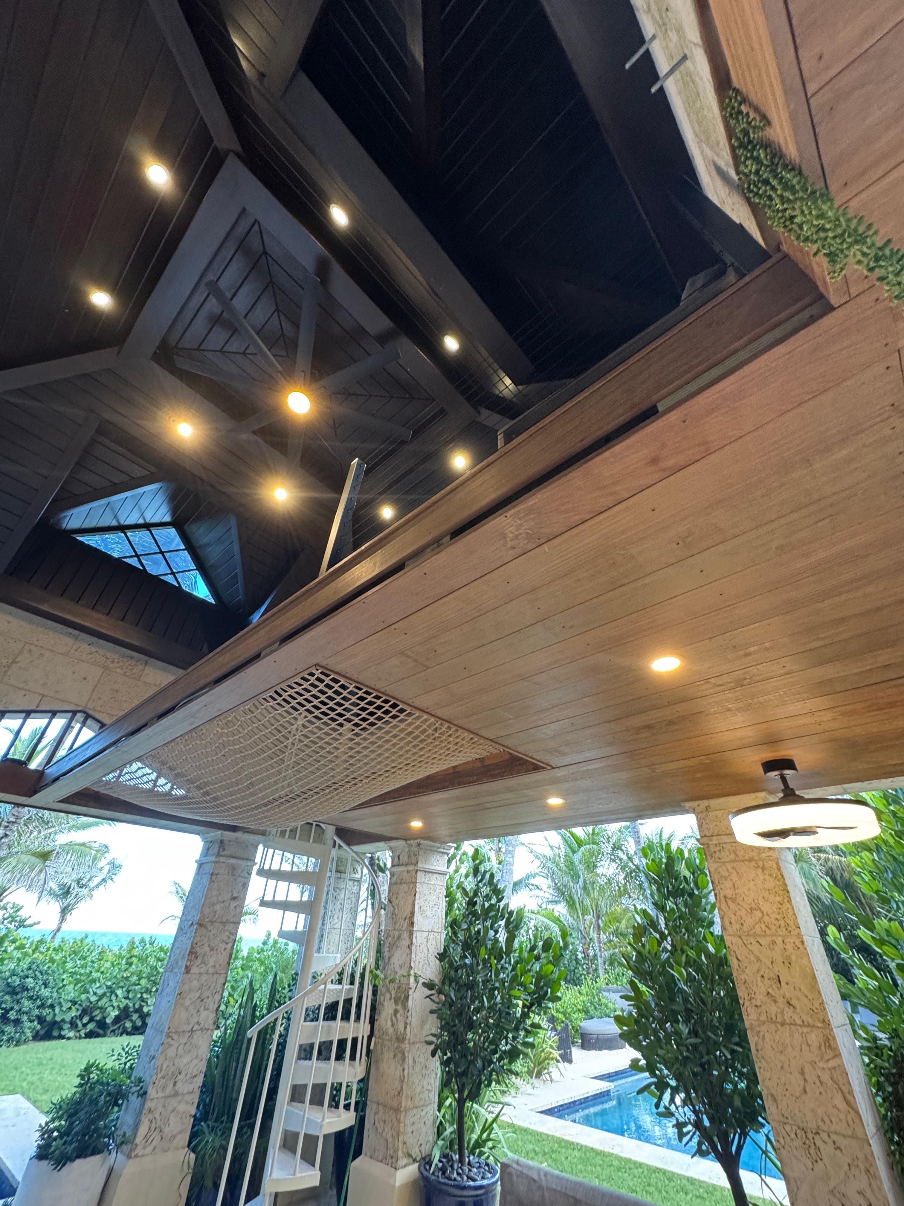 Outdoor covered living space with recessed lighting overlooking a pool