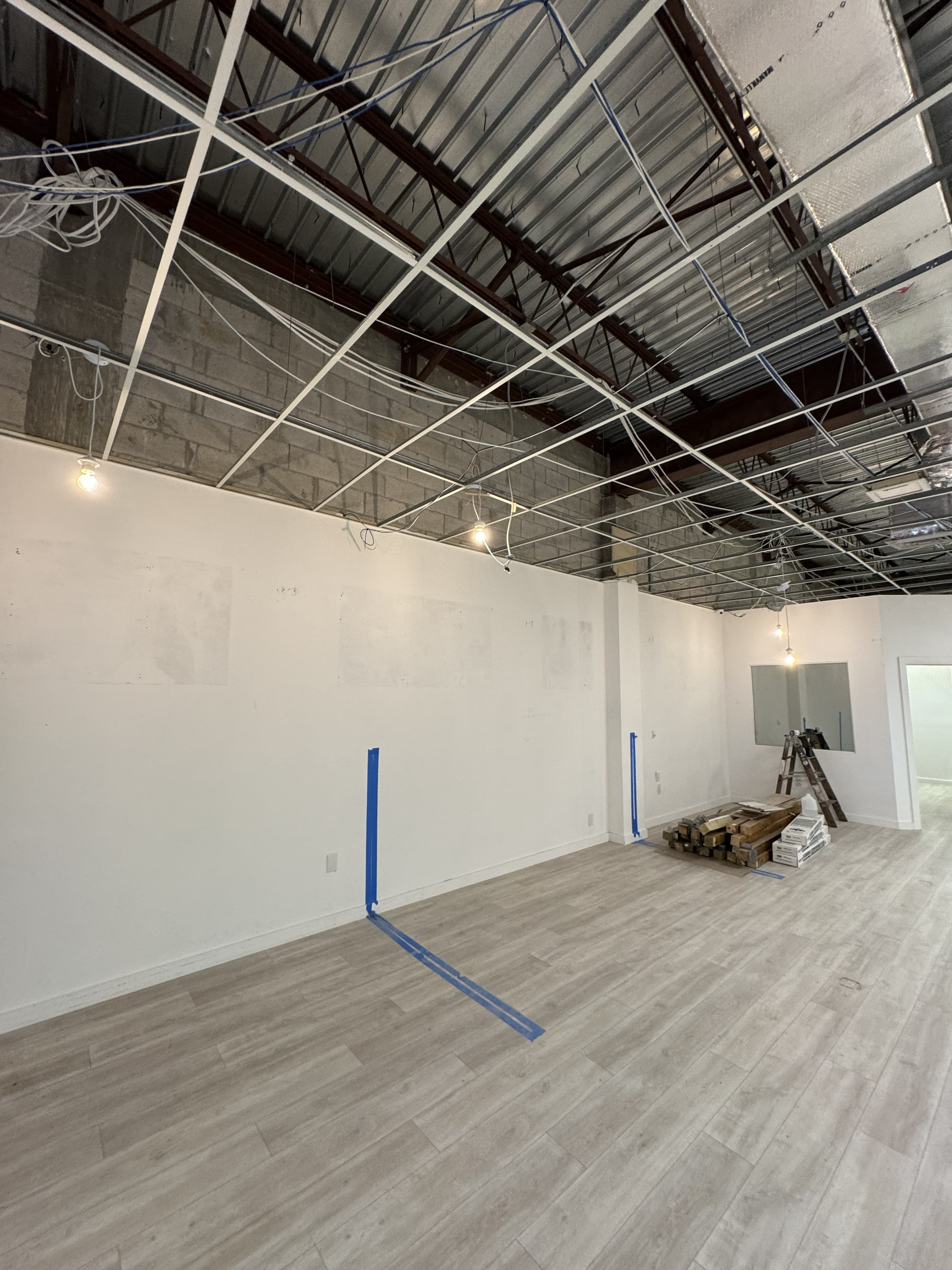 Open ceiling with electrical wiring and steel roof deck in a commercial retail shell space