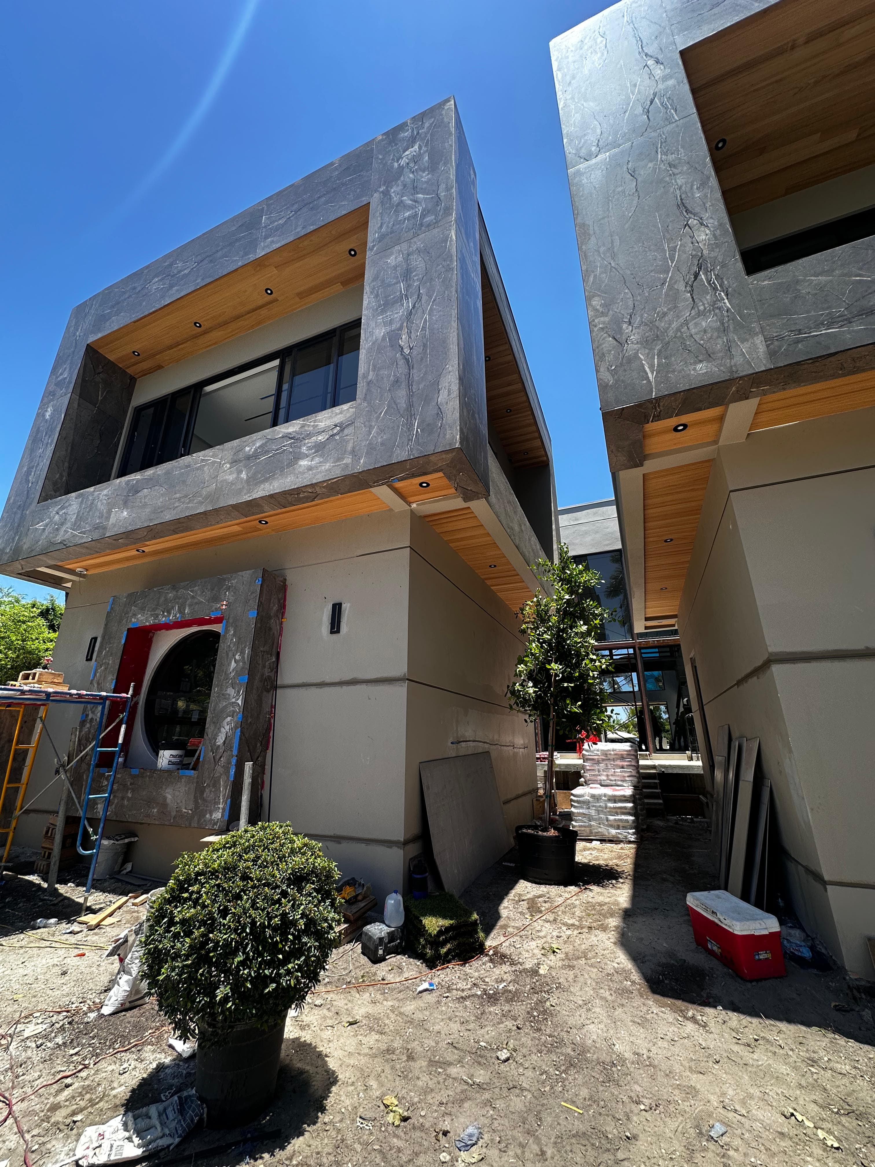 Modern residential new-construction project with stone exterior surfaces and recessed lighting integrated into wood soffits
