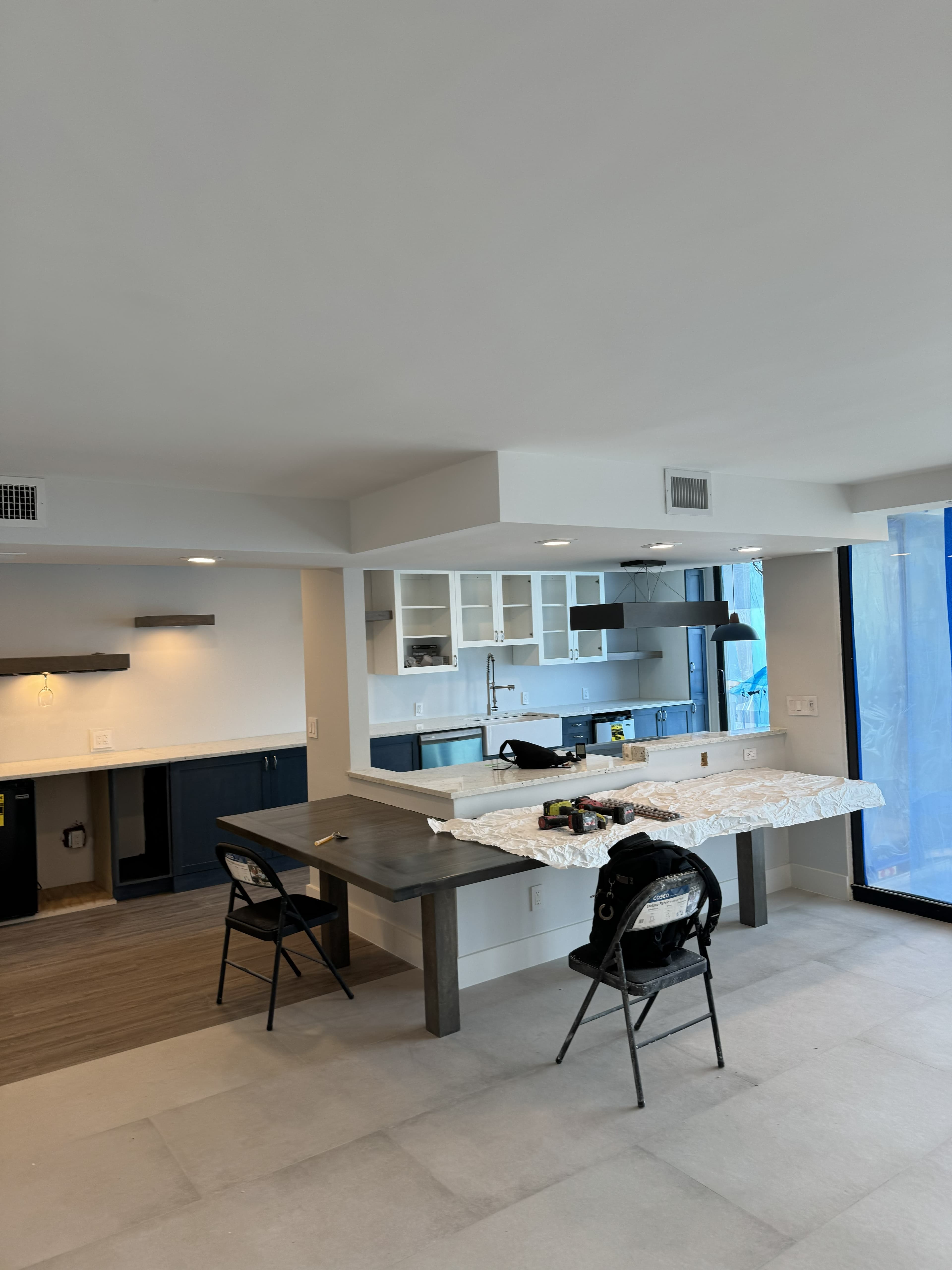 Renovated kitchen and living space with recessed, pendant, and under-cabinet lighting