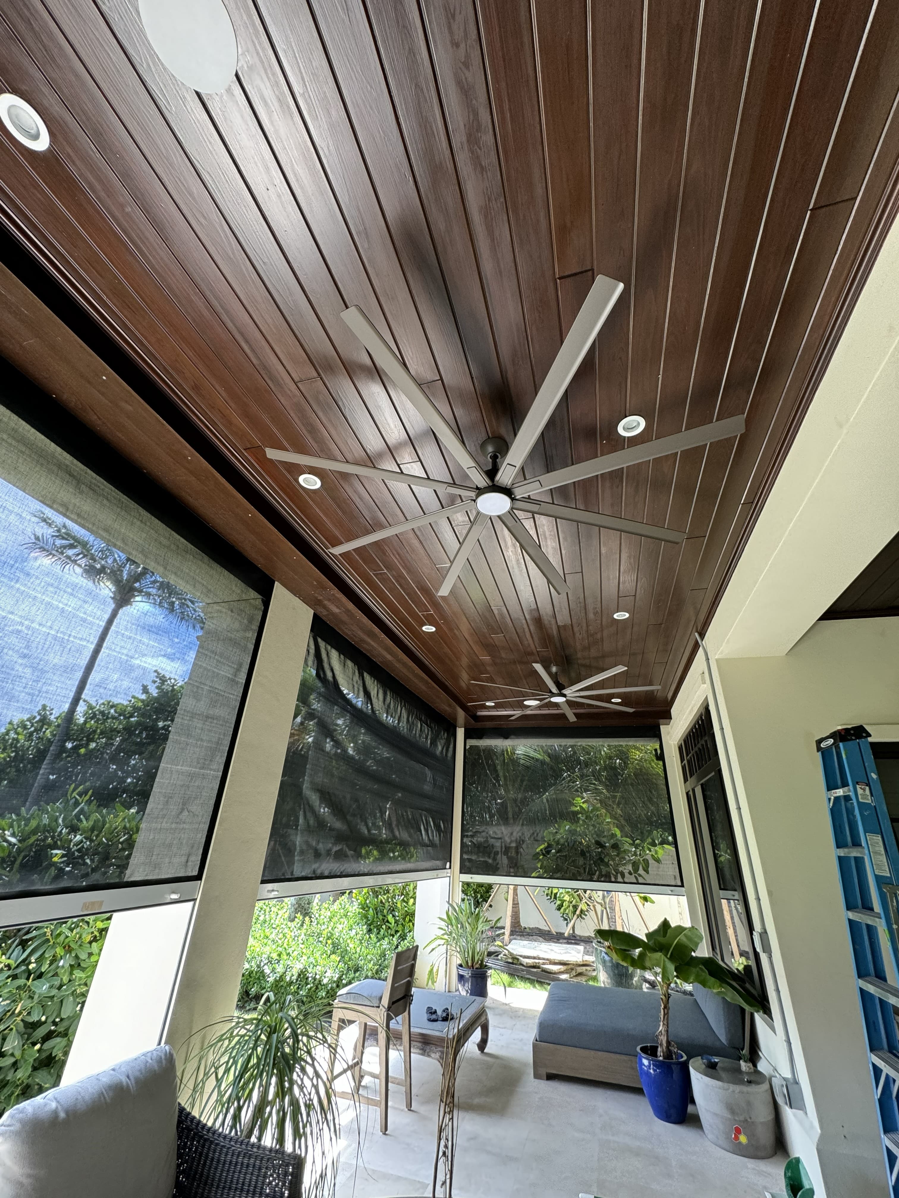 Covered residential outdoor living area with recessed lighting and ceiling fans