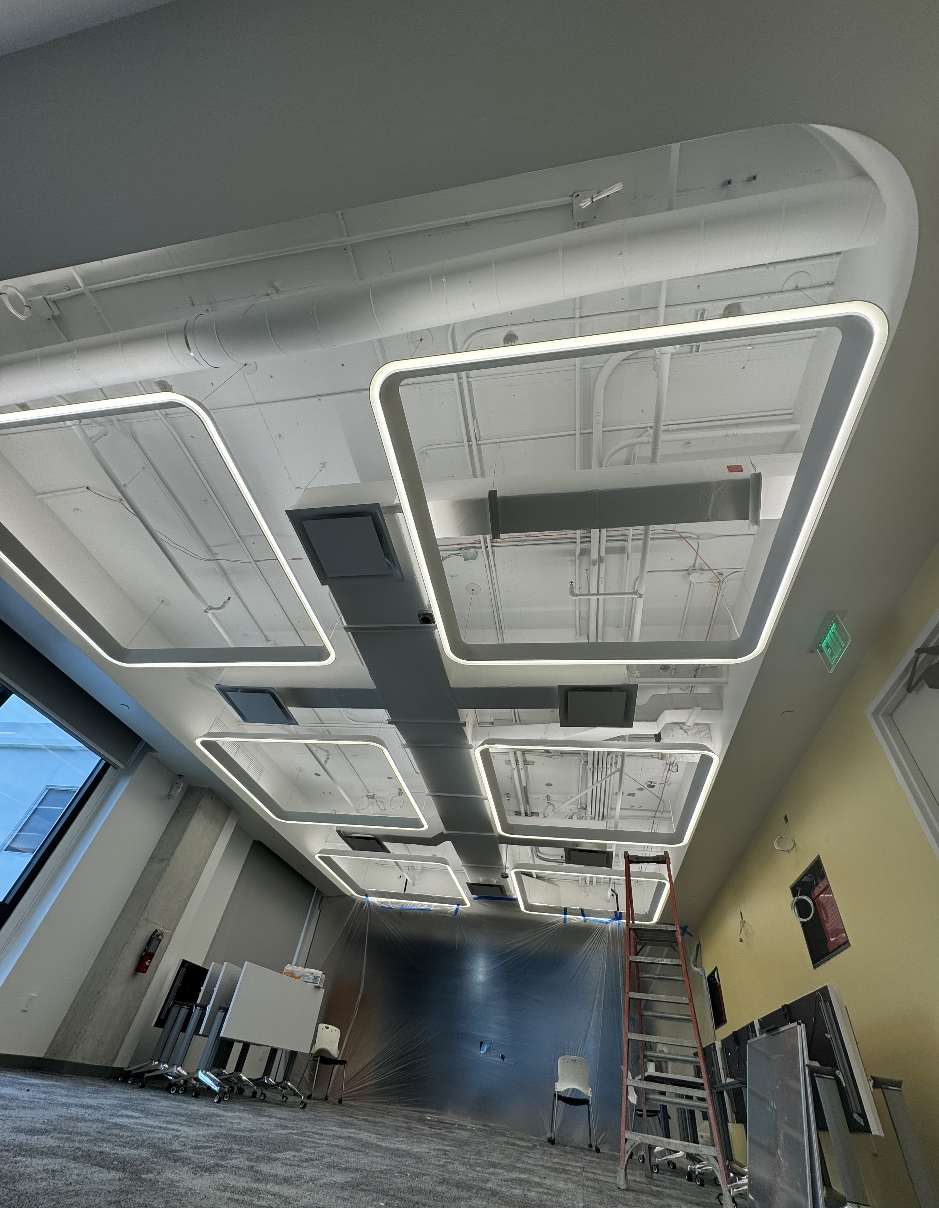 Geometric LED lighting and exposed conduit installation in a commercial office ceiling